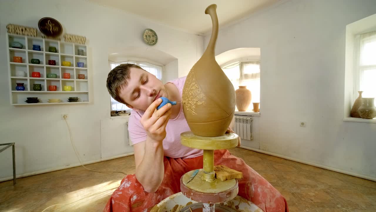 Potter decorating a clay vase on a pottery wheel