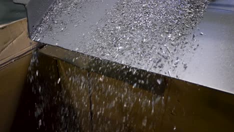 metal filings fall from a vibrating ramp into a large cardboard box