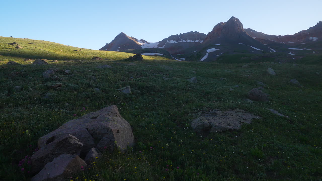 deslizador cinematográfico a la derecha flor silvestre hora de oro cuenca del lago de hielo silverton telluride nuestro camino cabeza de verano nieve derretida pico puesta de sol en las montañas rocosas valle tarde crepúsculo paisaje impresionante
