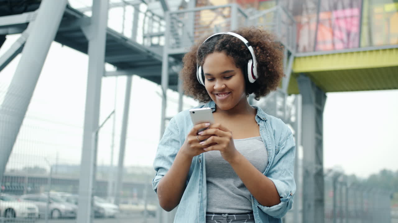 Ragazza adolescente con le cuffie che usa lo smartphone