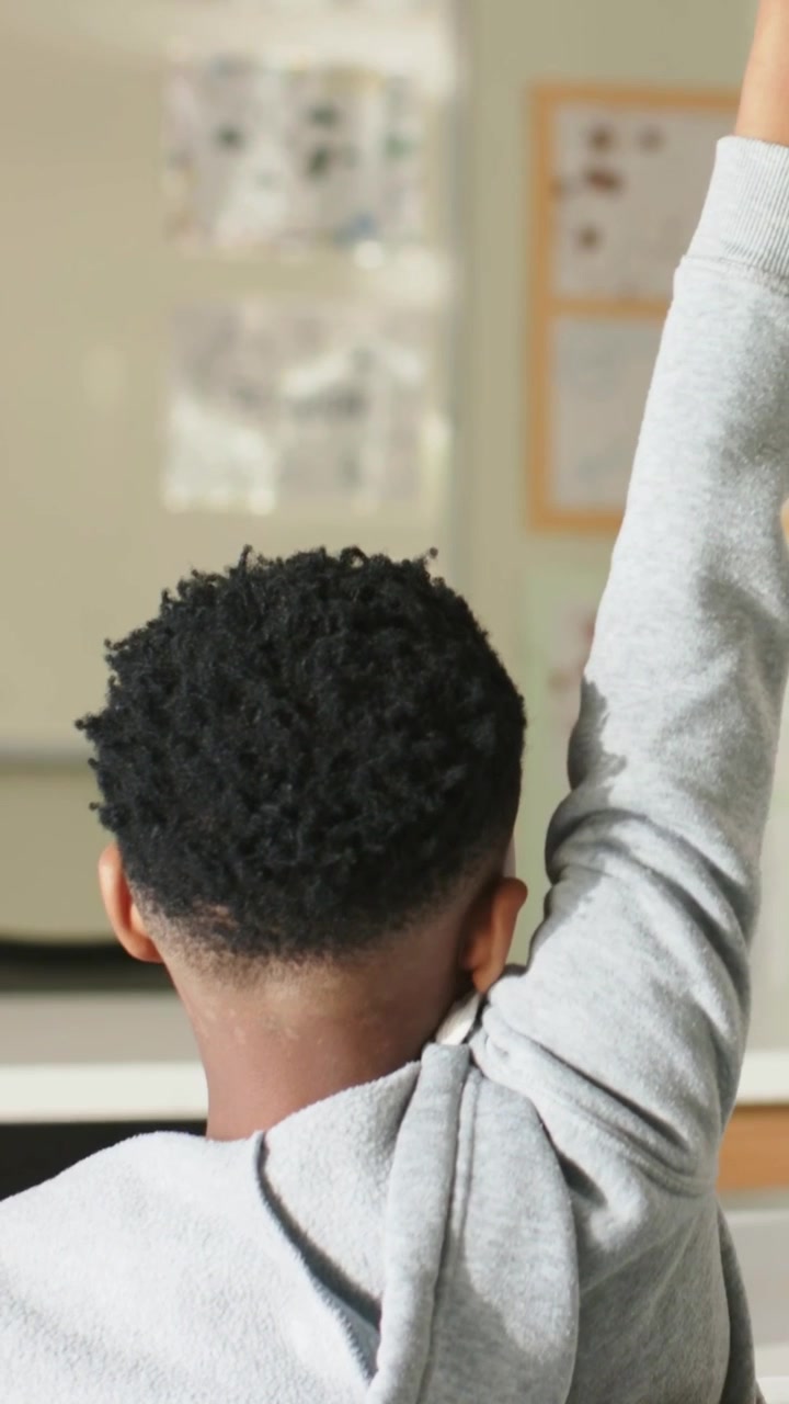 Verticale video: Opstaande student in grijze hoodie na het verplaatsen aan de voorkant van het klaslokaal, gele stoel.