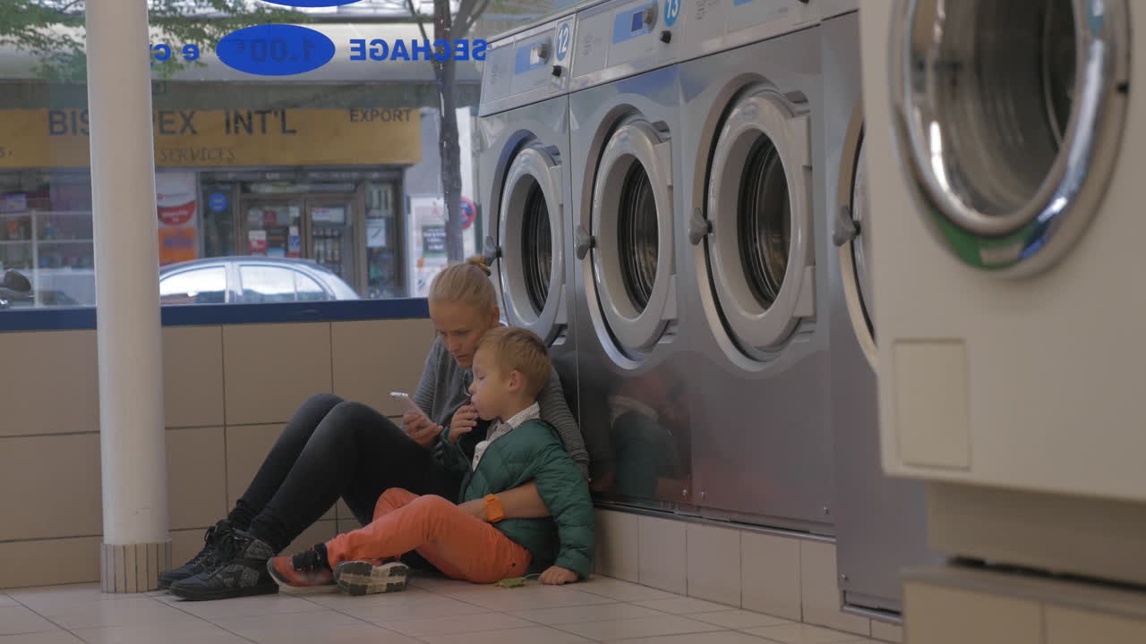 Mother and child using mobile in the laundry