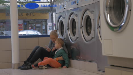 mother and child using mobile in the laundry