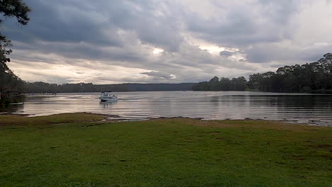 fishing boat coming ashore on a lake in the evening with dark clouds on a calm day