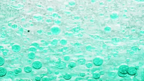 macro shot of blue bubbles in water moving right with yellow background