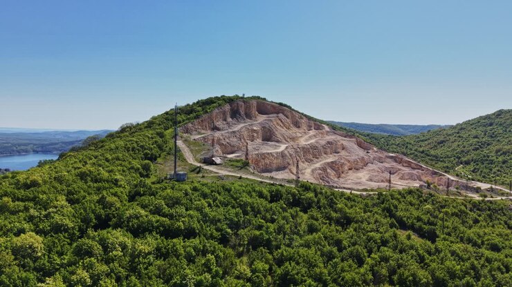 Colline verdi con alberi e una torre in lontananza sotto un cielo sereno.