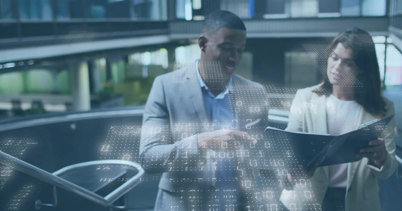 Business colleagues reviewing document in office atrium, showing binary code overlay