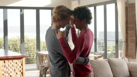 una pareja gay feliz y diversa bailando en la sala de estar en casa, en cámara lenta