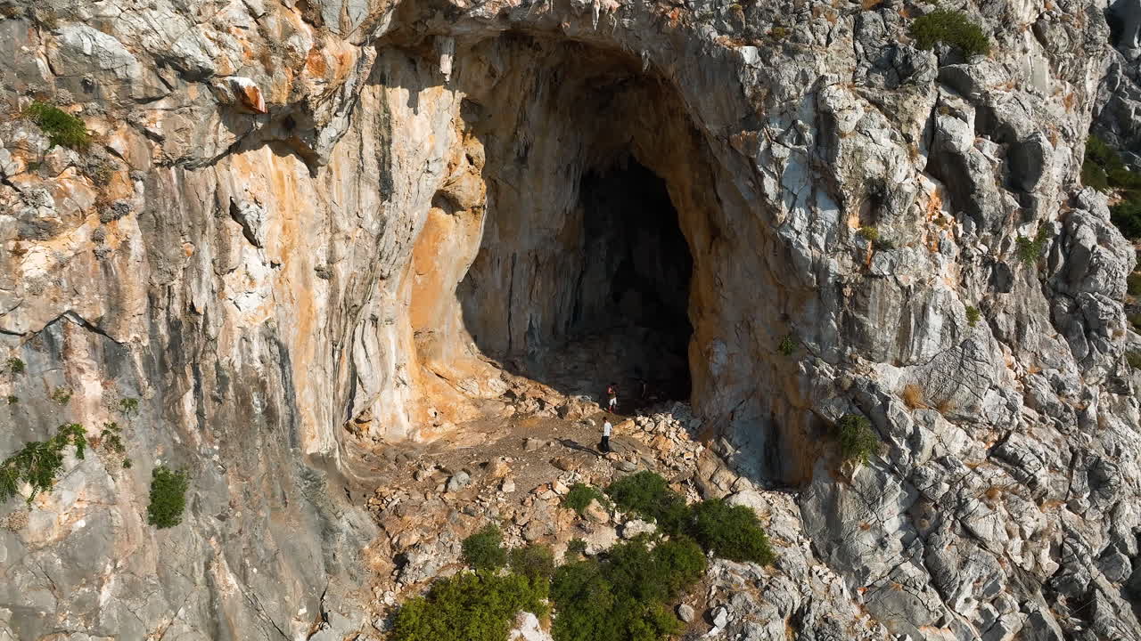 Drone circling hikers inside a cave on the coast of Rhodes, Greece, sunny day