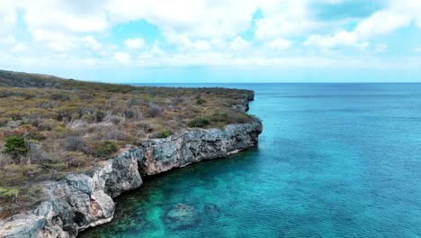 el dron está volando alrededor de acantilados sobre el océano en curacao imágenes aéreas 4k