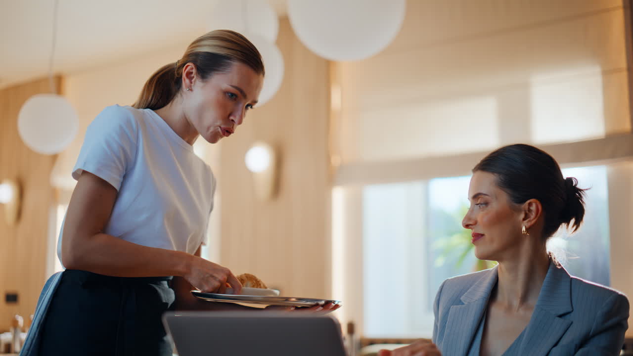 Smilende servitør som serverer kaffe på restaurant nærbilde. Kvinne som jobber på laptop