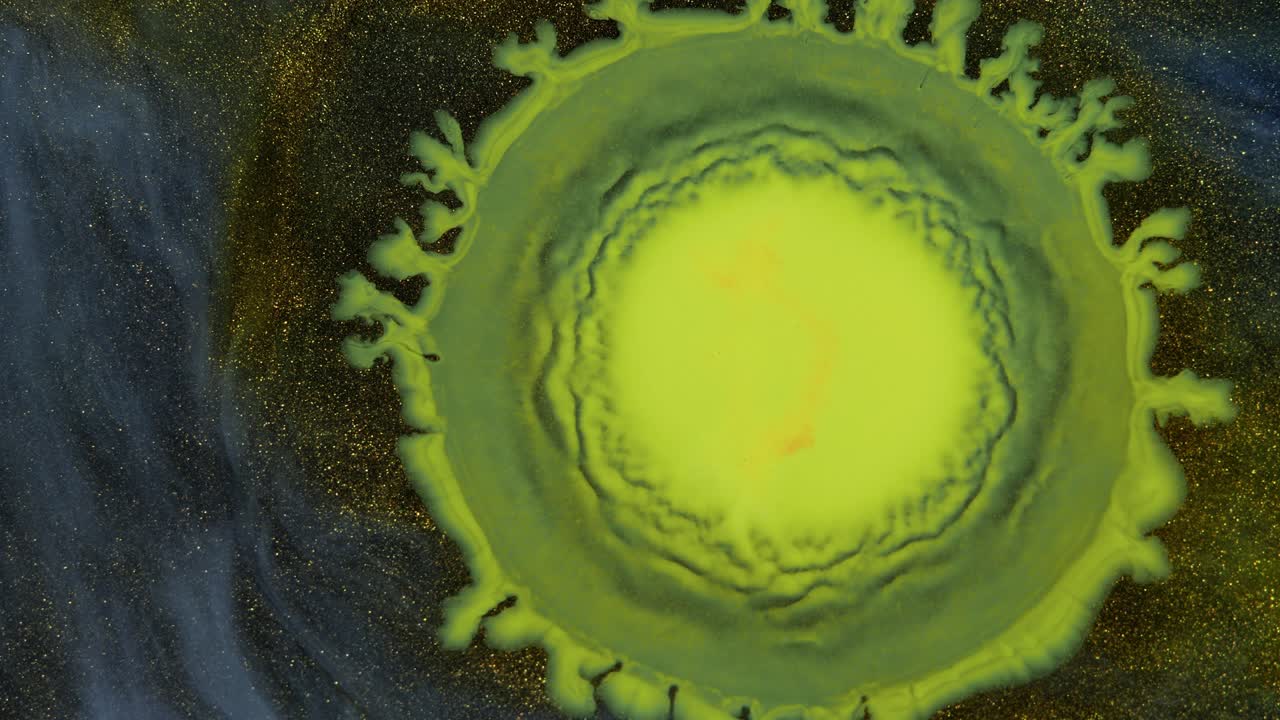 la gota amarilla de pintura crece en el oro brumoso. espacios profundos.