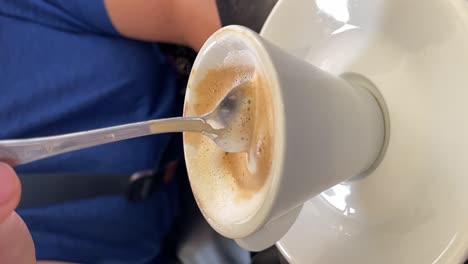 Close-up-vertical-video-shot-an-espresso-coffee-foam-stirred-with-a-metal-spoon