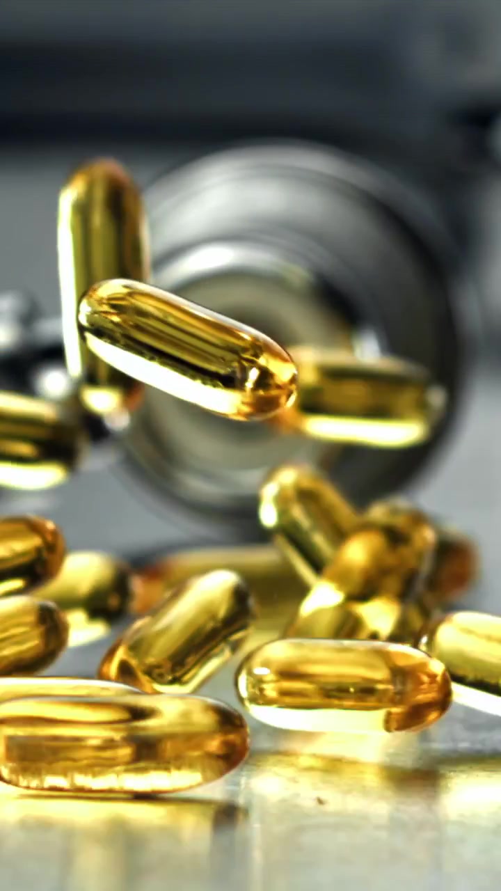 Capsule dorate di Omega-3 che cadono al rallentatore