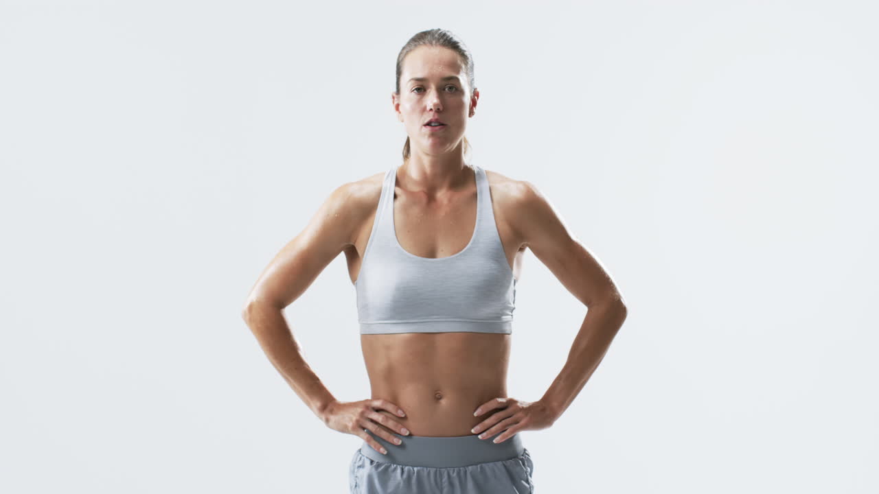 Fit young Caucasian woman athlete stands confidently on a white background, with copy space