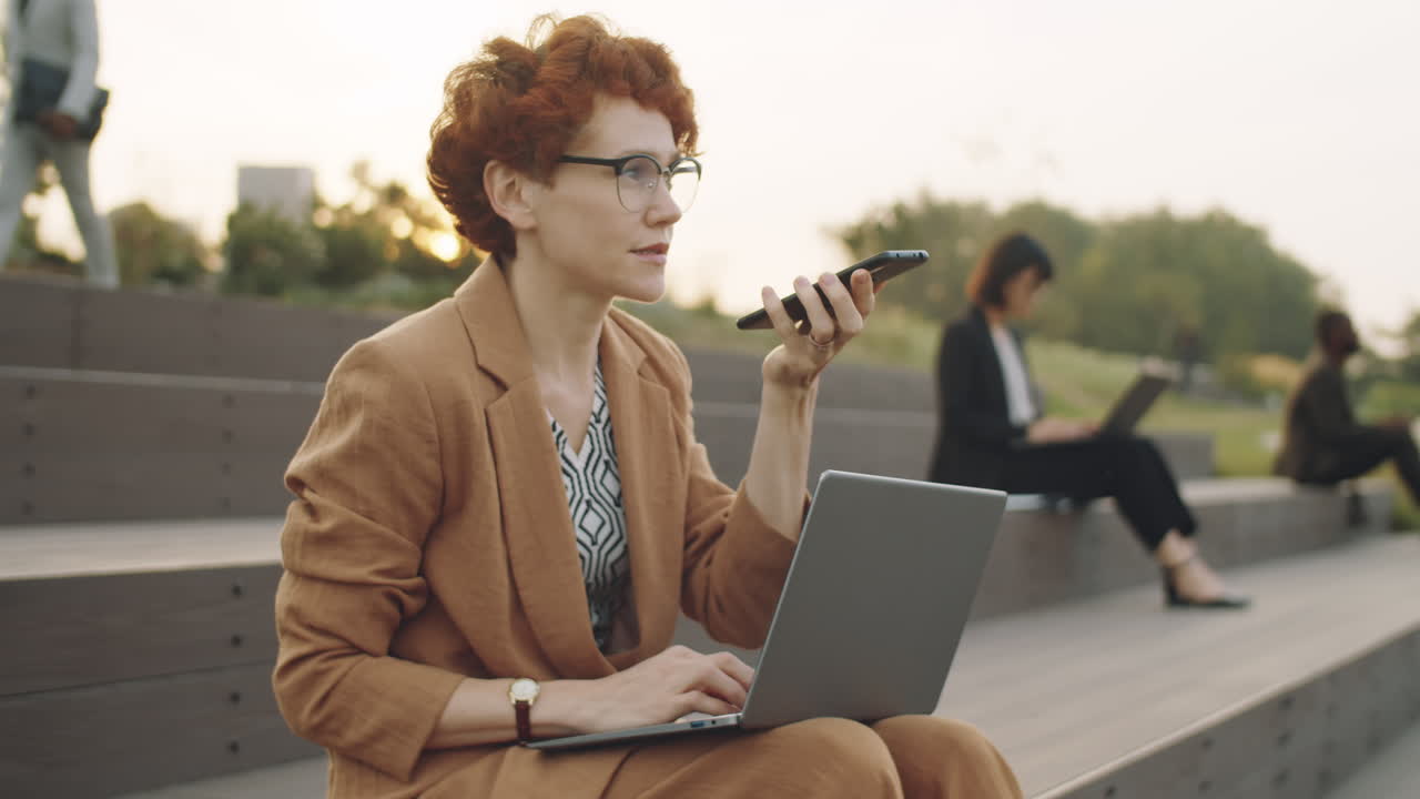 외부에서 전화로 음성 메시지를 녹음하는 사업가