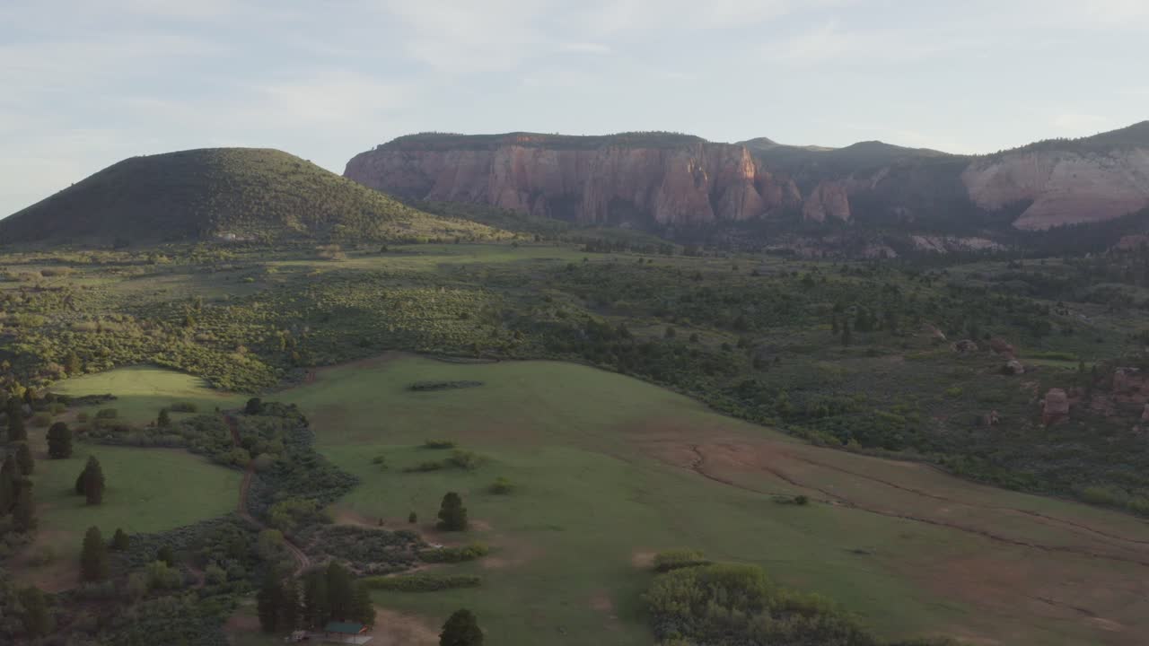 sacando una amplia vista escénica de un valle de hierba verde con acantilados rocosos en el parque nacional zion