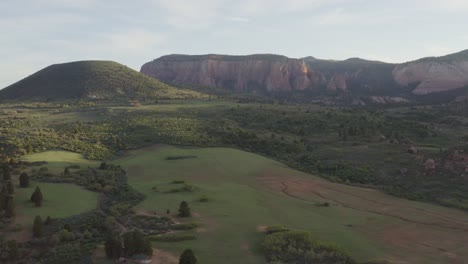 pulling out wide scenic view of a green grass valley with rocky cliffs in zion national park