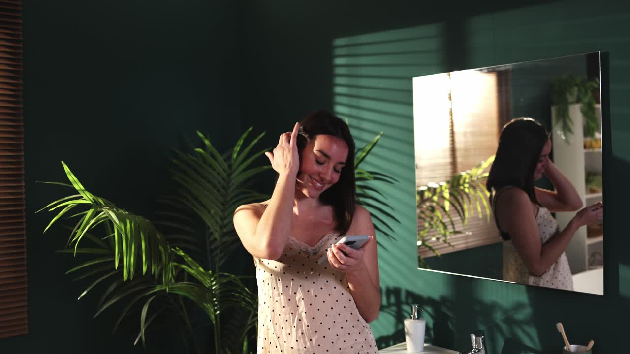 Giovane donna che sorride e usa lo smartphone in un bagno moderno