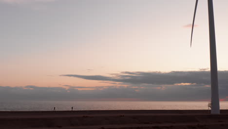 Windkraftanlagen-Und-2-Silhouetten-Von-Menschen,-Die-Während-Des-Sonnenuntergangs-Auf-Der-Insel-Neeltje-Jans,-Niederlande,-Auf-Dem-Deich-Spazieren-Gehen