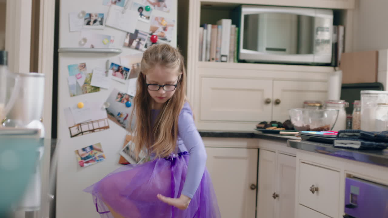 una bailarina feliz bailando en la cocina divirtiéndose practicando movimientos de baile de ballet usando tutu púrpura en casa