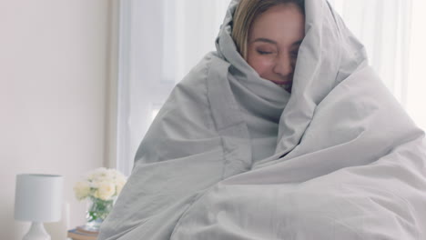 hermosa mujer jugando en la cama escondiéndose bajo una manta divirtiéndose disfrutando de una mañana lúdica en casa