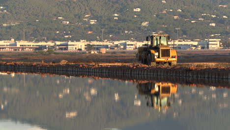 Glatt-Folgen-Sie-Einem-Traktor,-Der-Sich-Im-Wasser-Der-Salinas-De-Ibiza,-Spanien,-Widerspiegelt