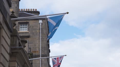 scottish and british flag on facade flagpoles on royal mile, edinburgh