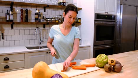 mujer cortando zanahorias en el mostrador de la cocina