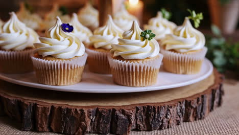 a display of frosted cupcakes on a rustic two-tiered stand, illuminated by candles