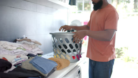 african american man doing laundry at home, slow motion