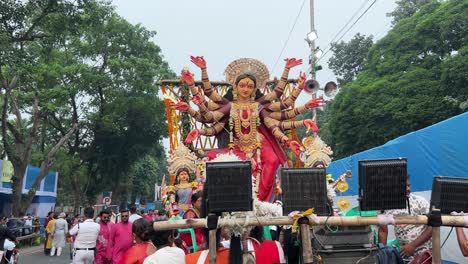 dancing durga idol at durga puja with people walking on the road at the procession at red road in kolkata, india.