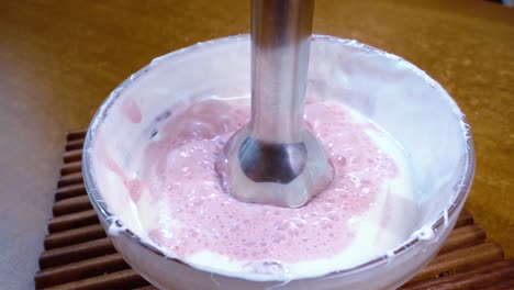 beaten eggs with sugar and strawberries using a mixer.slow motion with rotation tracking shot.