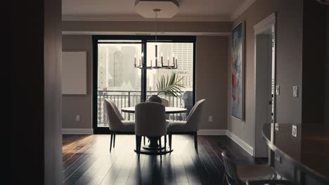 revealing shot of a dining room table setup with a circular table, white chairs, and a patio door letting in natural sunlight