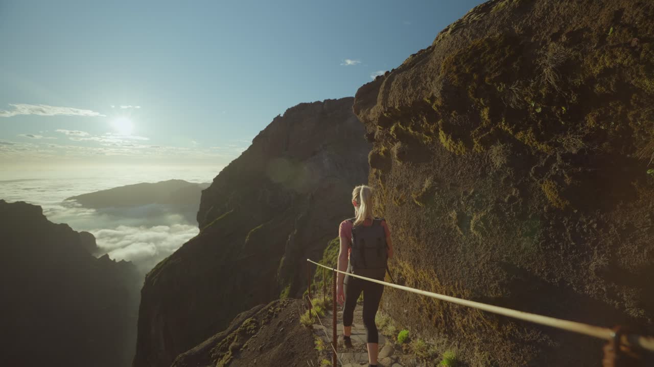 excursionista femenina bajando las escaleras en el paisaje volcánico durante un atardecer brillante