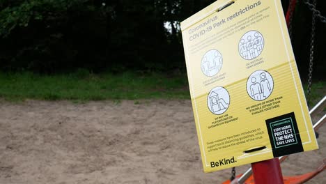 primer plano del parque público covid corona virus señal de advertencia junto al columpio del patio de recreo