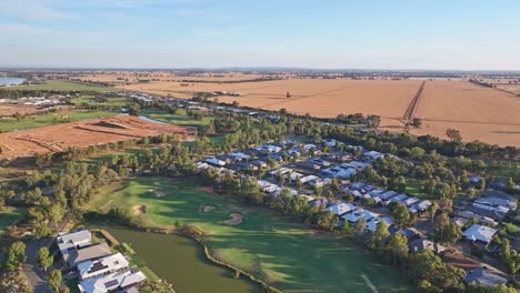 Sobre-Un-Campo-De-Golf-Y-Una-Zona-Residencial-Con-Campos-De-Trigo-Y-Una-Nueva-Zona-De-Construcción-Más-Allá,-Cerca-De-Yarrawonga