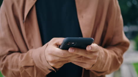 student hands chatting phone outdoor closeup. unknown man texting smartphone