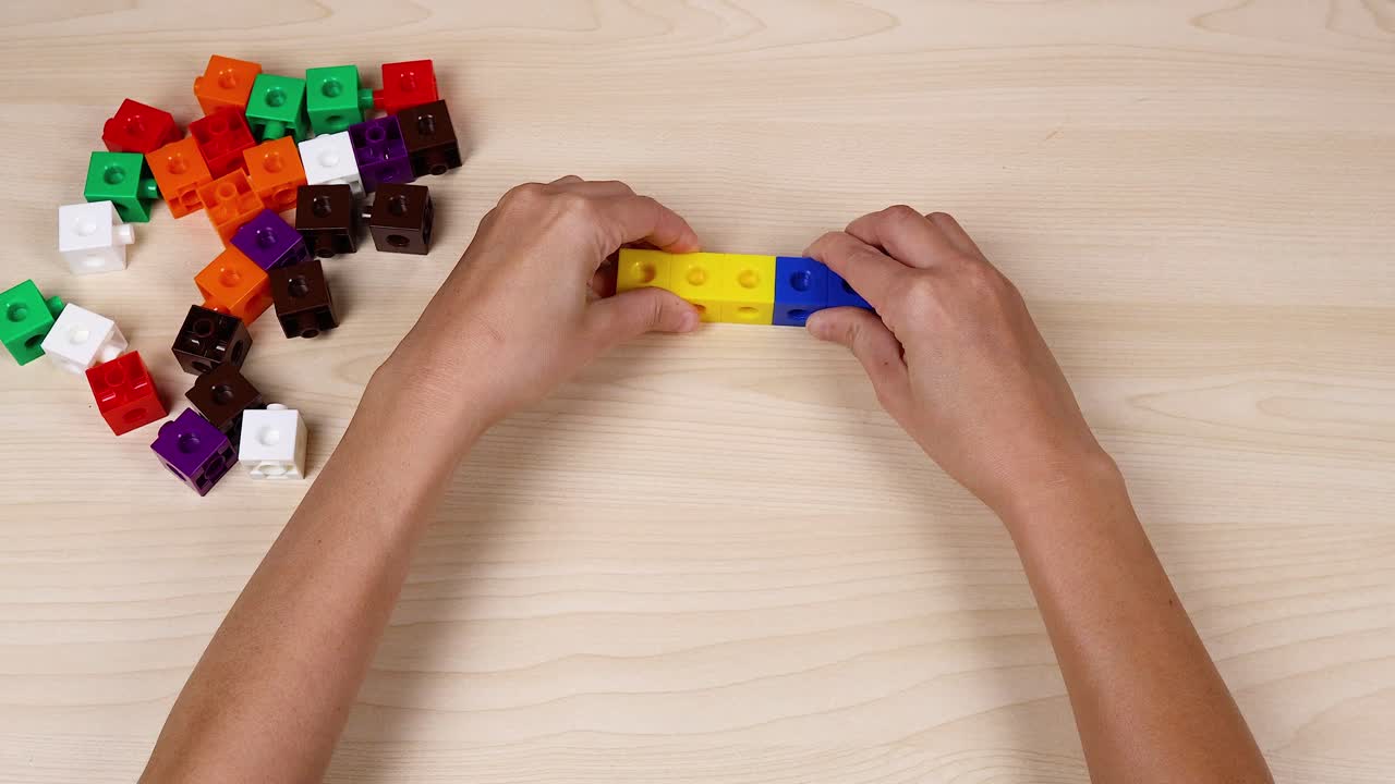 Hands assembling colorful cubes on a table