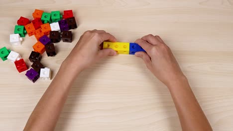 hands assembling colorful cubes on a table