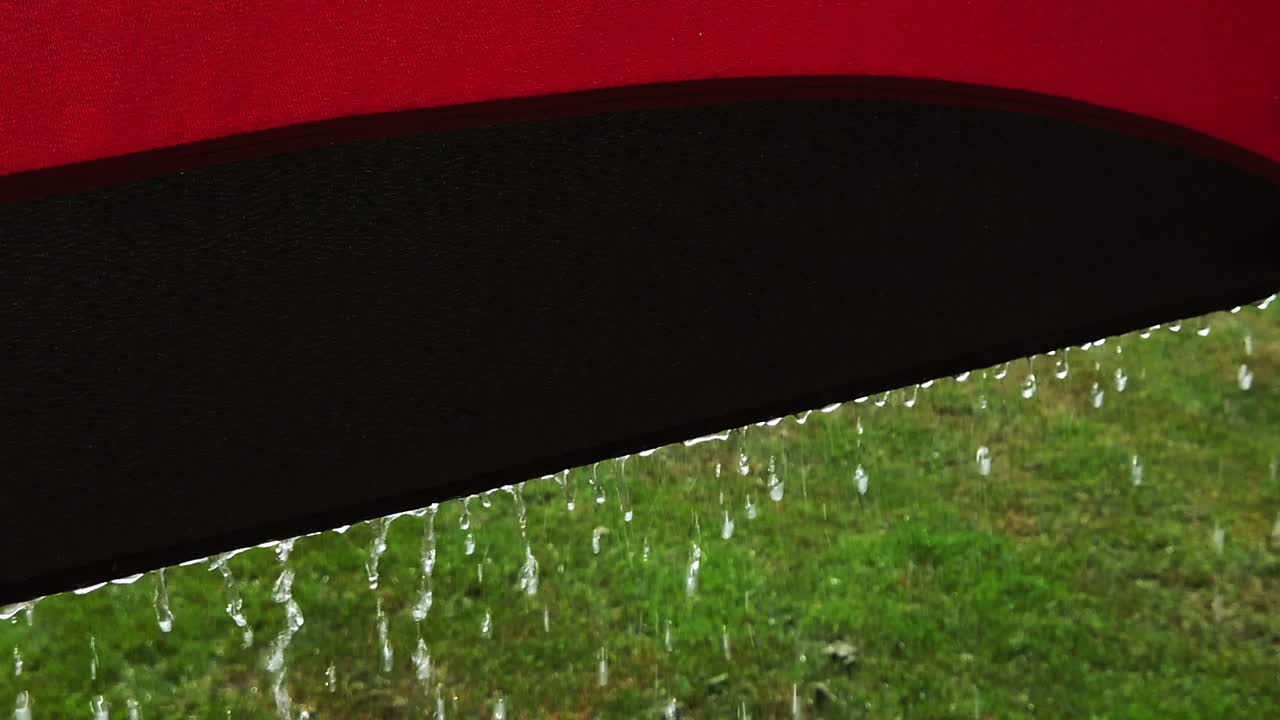 우산 가장자리에서 떨어지는 빗방울의 슬로우 모션 미디엄 샷