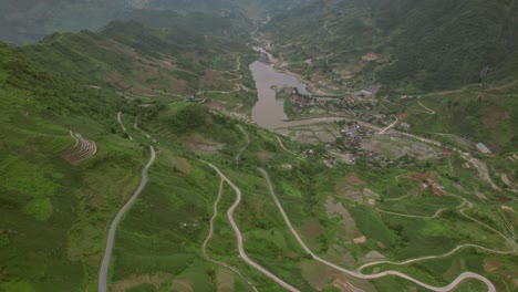 vista aérea hacia atrás de la aldea en el medio de una cuenca con un lago