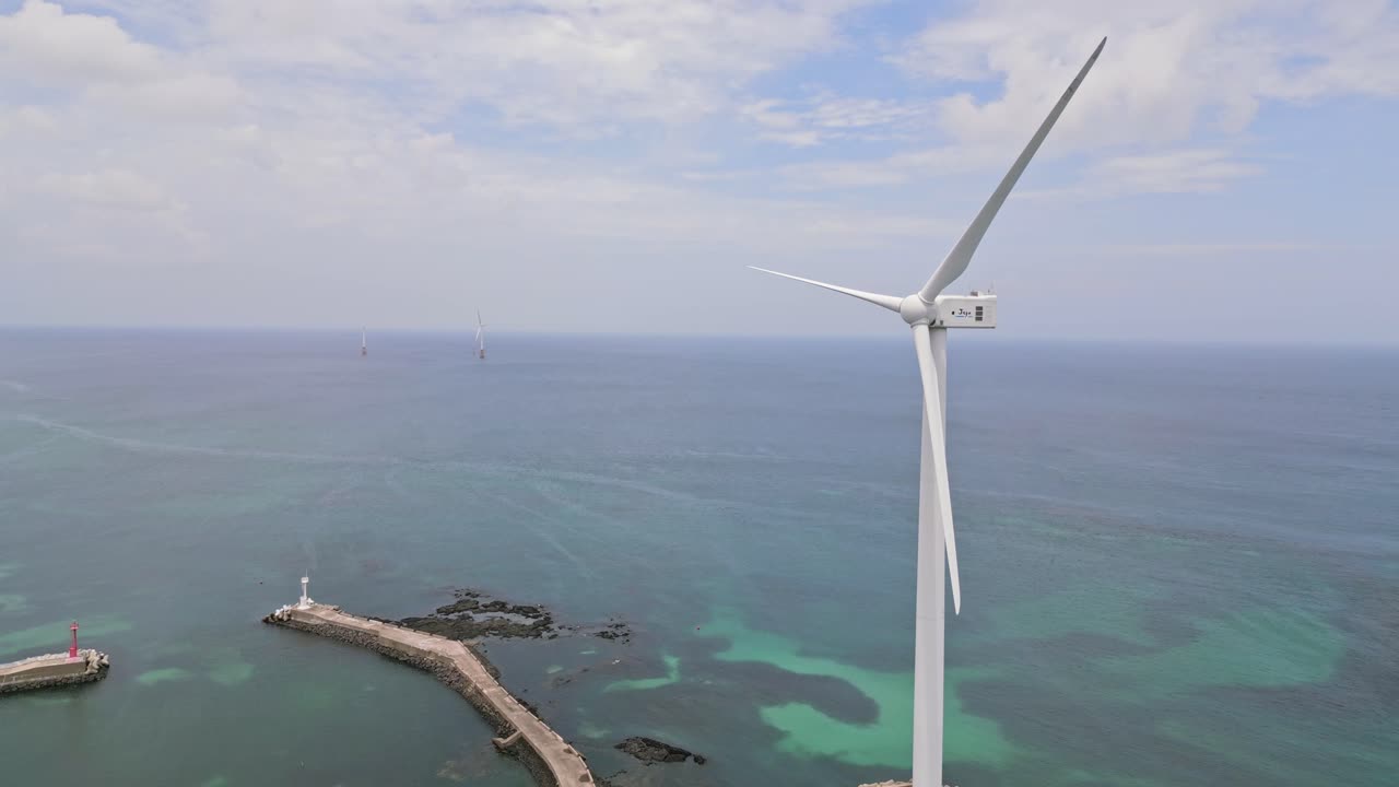Stunning drone view of Woljeong Beach's pristine shores, a tranquil oasis on beautiful Jeju Island, with a unique view of Wind Turbines in right on the waters edge