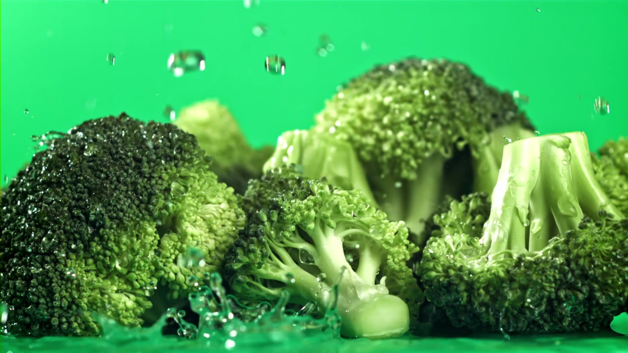 Cimette di broccoli freschi con schizzi d'acqua su sfondo verde
