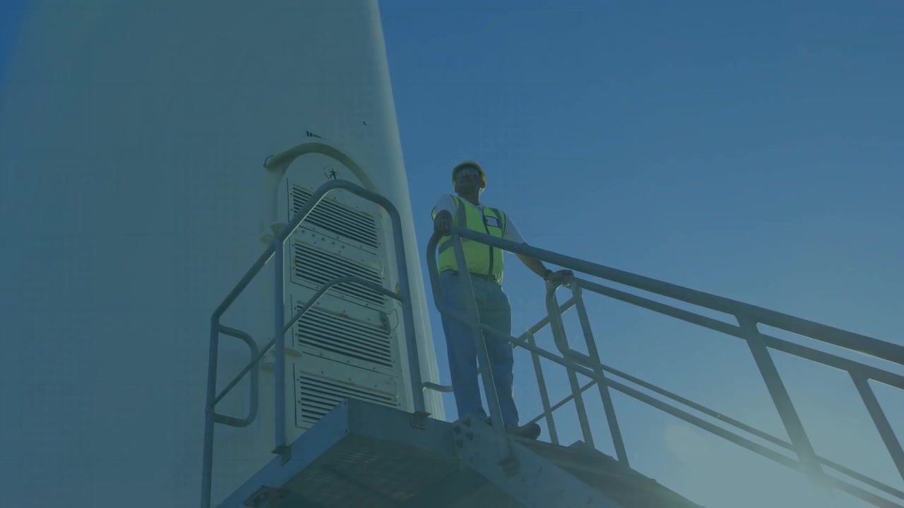 Con una sovrapposizione a griglia che appare sulla torre eolica, un tecnico monitora i grafici che tracciano le prestazioni.