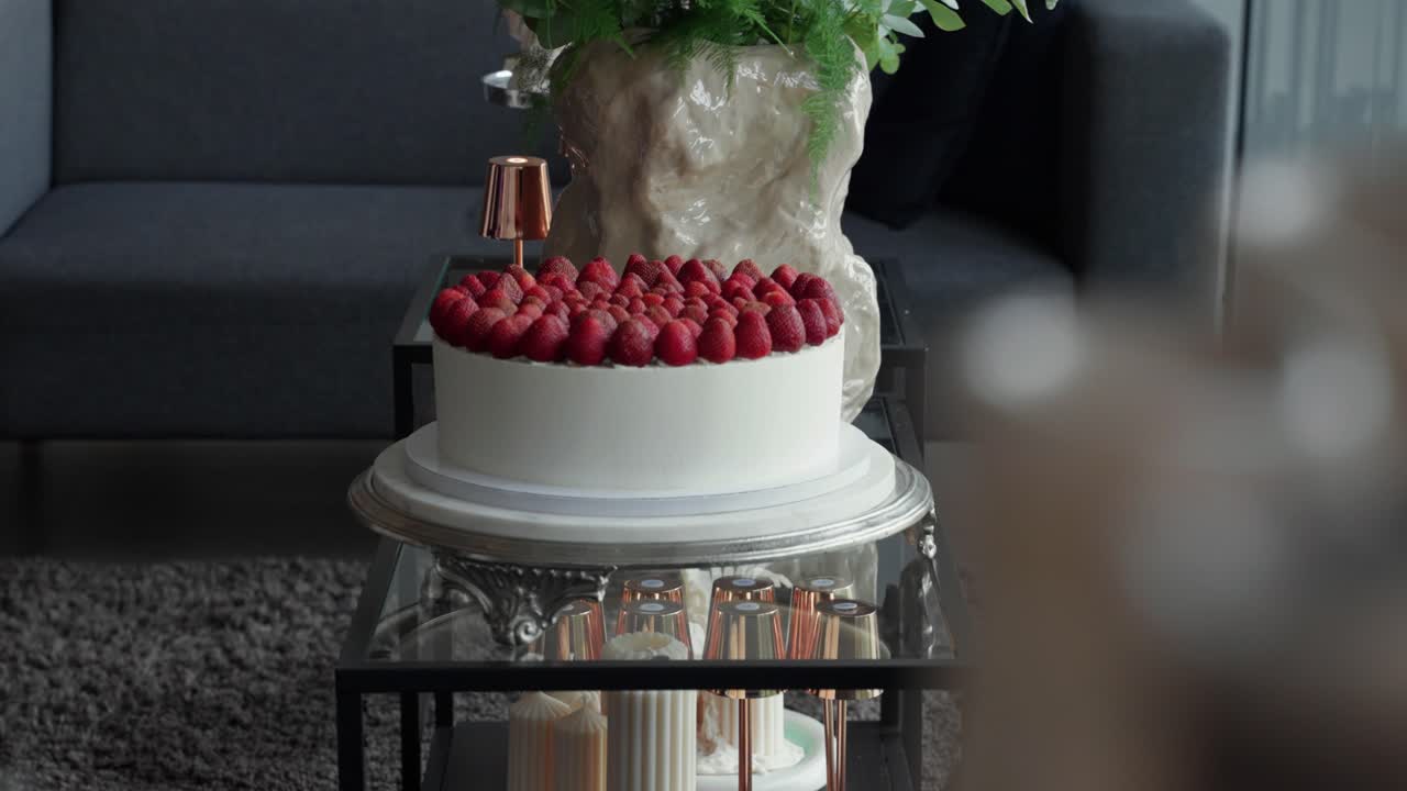 Elegant white cake topped with fresh strawberries placed on a decorative table in a stylish indoor event setting. Perfect for weddings, celebrations, or gourmet dessert showcases