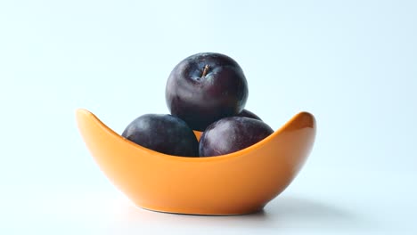 plums in an orange bowl