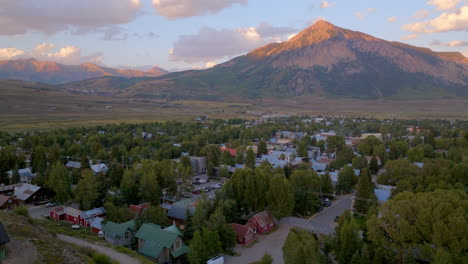 Antena-De-Crested-Butte-En-Colorado-Con-Sol-En-La-Montaña-Y-Una-Panorámica-Hacia-Una-Nueva-Construcción-A-La-Izquierda-Al-Atardecer