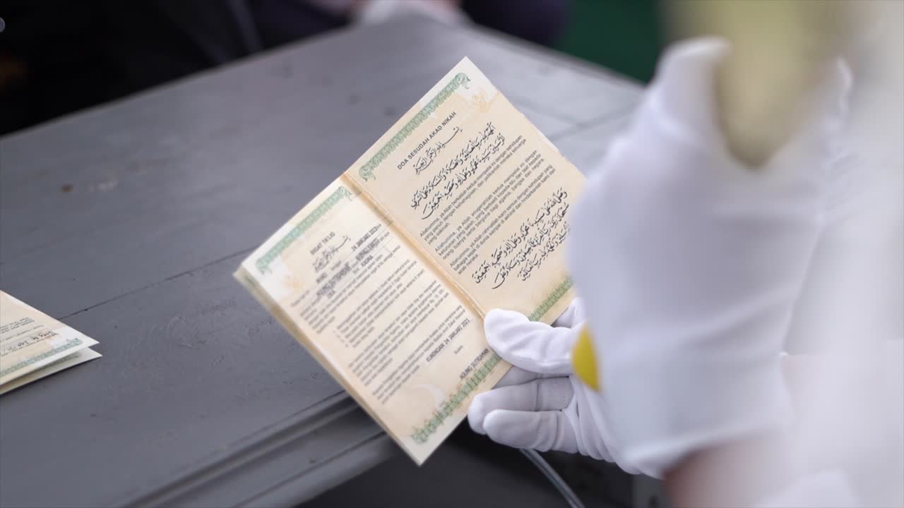 Lo sposo legge Sighat taklik nel libro di matrimonio al suo matrimonio, che è un contratto che può servire da promemoria per il marito riguardo ai suoi obblighi e responsabilità.