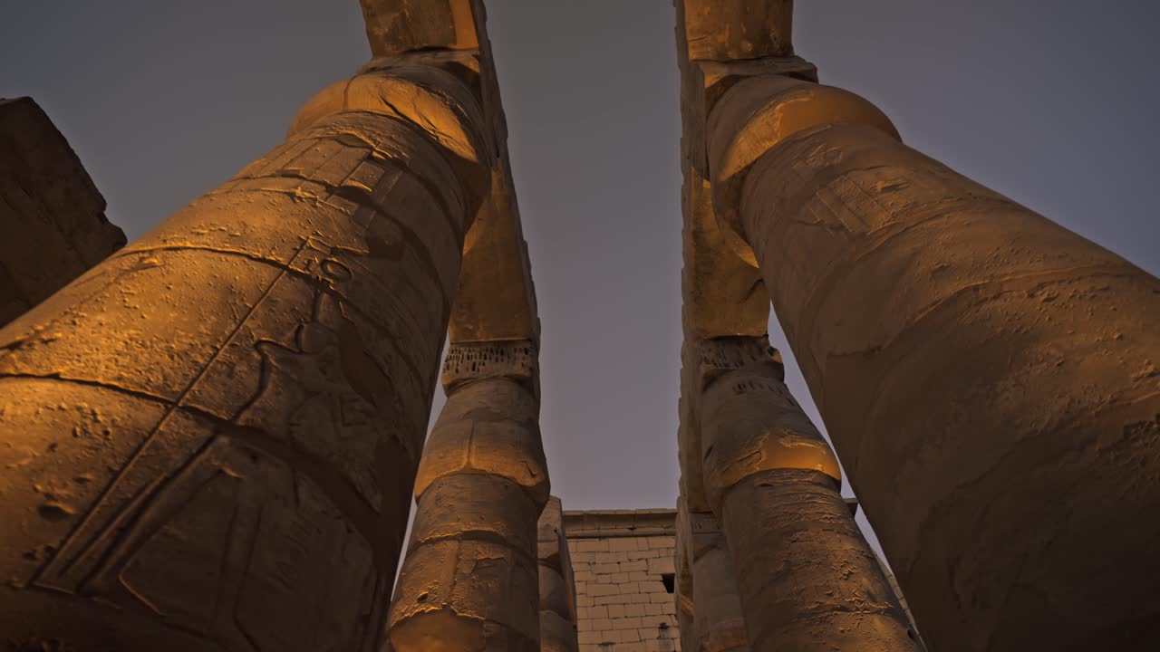 Inquadratura dal basso che guarda verso il cielo tra le imponenti colonne del Tempio di Luxor in Egitto.